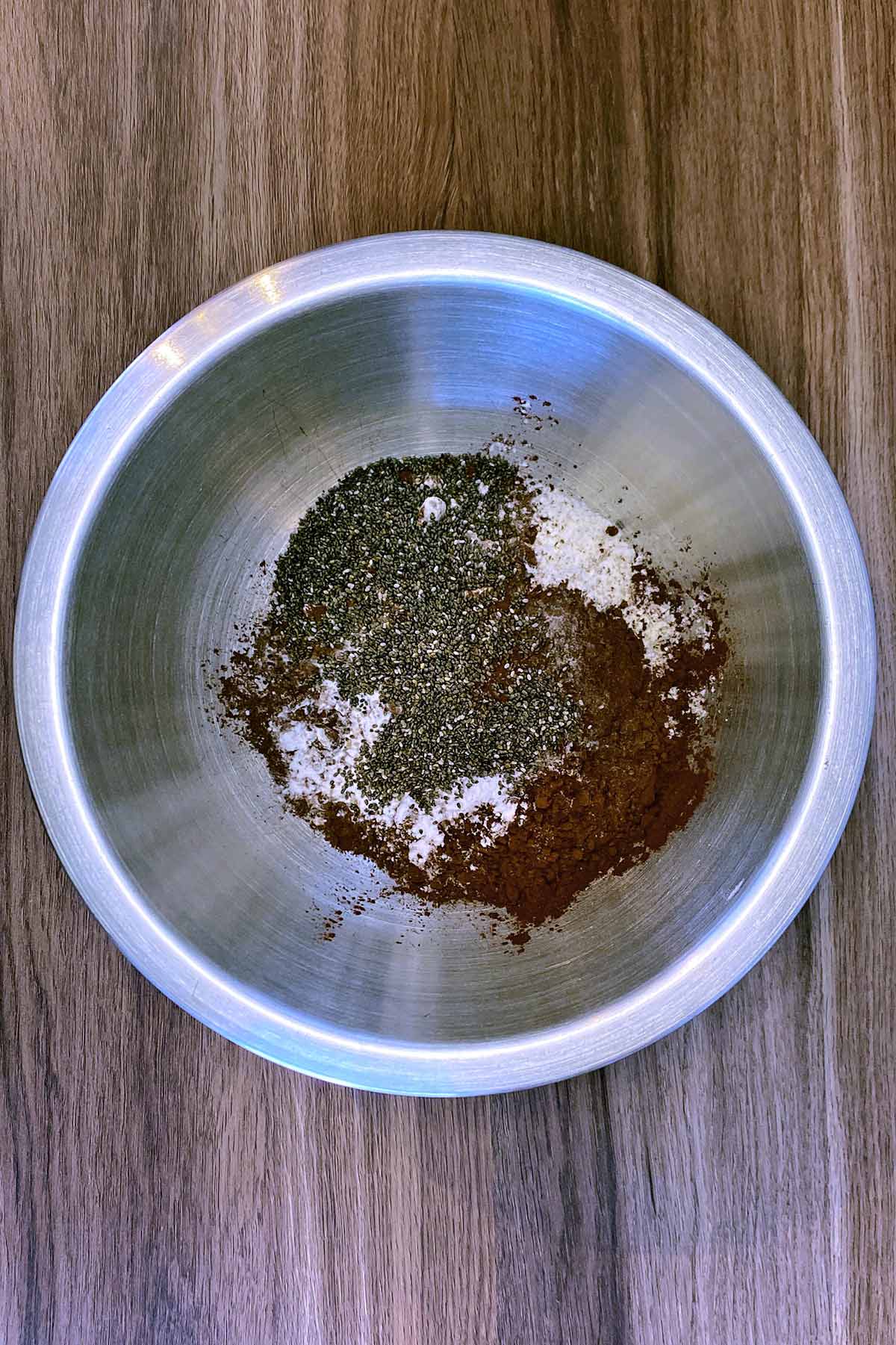 A large bowl containing flour, cocoa powder, baking powder, baking soda and chia seeds.