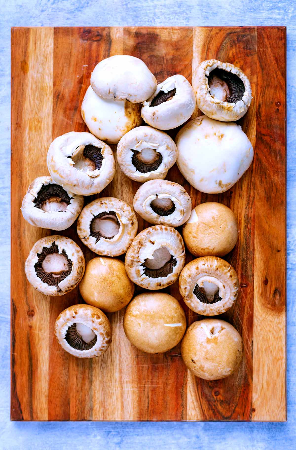 A wooden chopping board with a selection of mushrooms on it.