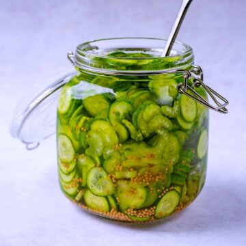 Quick pickled cucumbers in an open glass jar.