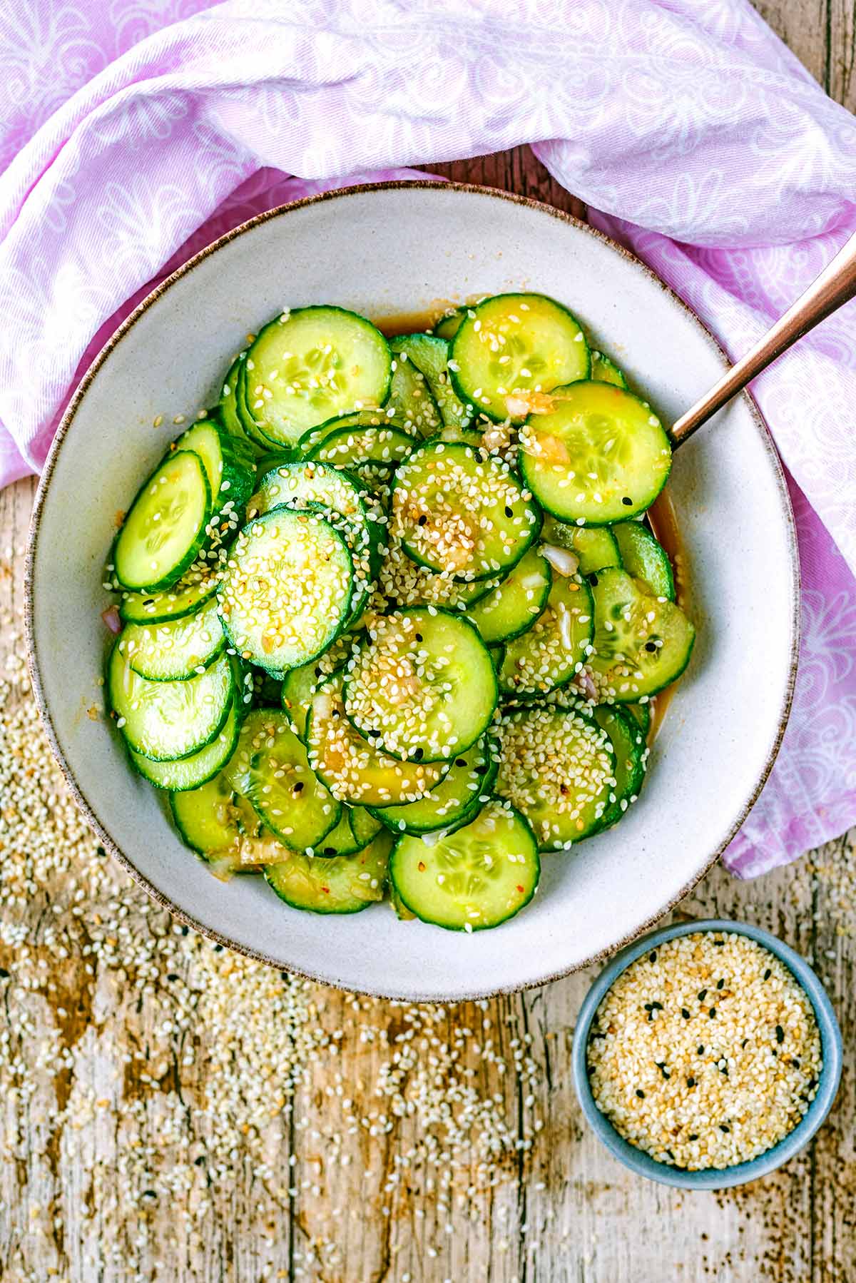 Asian cucumber salad in a bowl next to a pink towel.