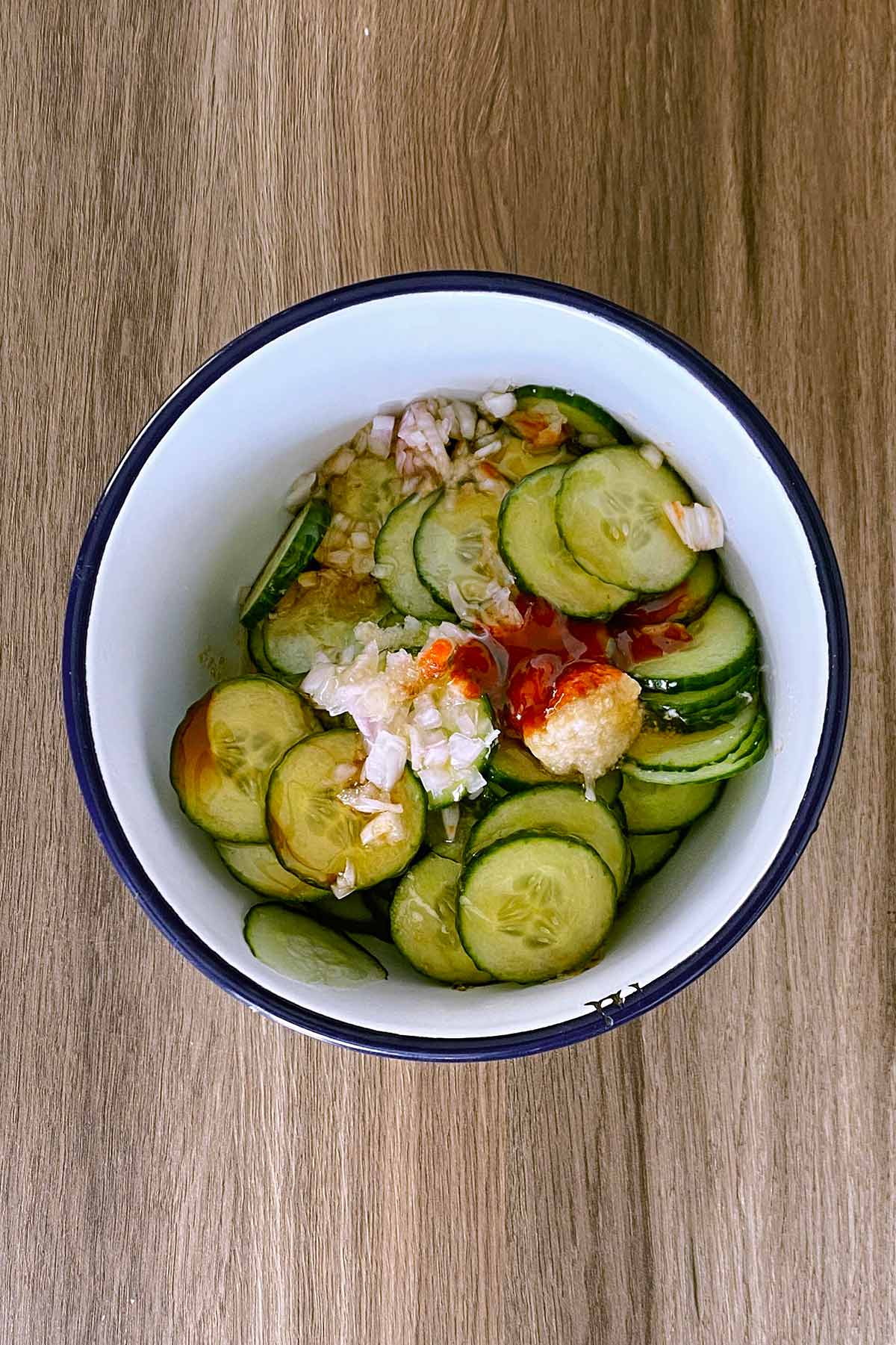 Garlic, ginger, chopped shallots and sauces added to the cucumber.