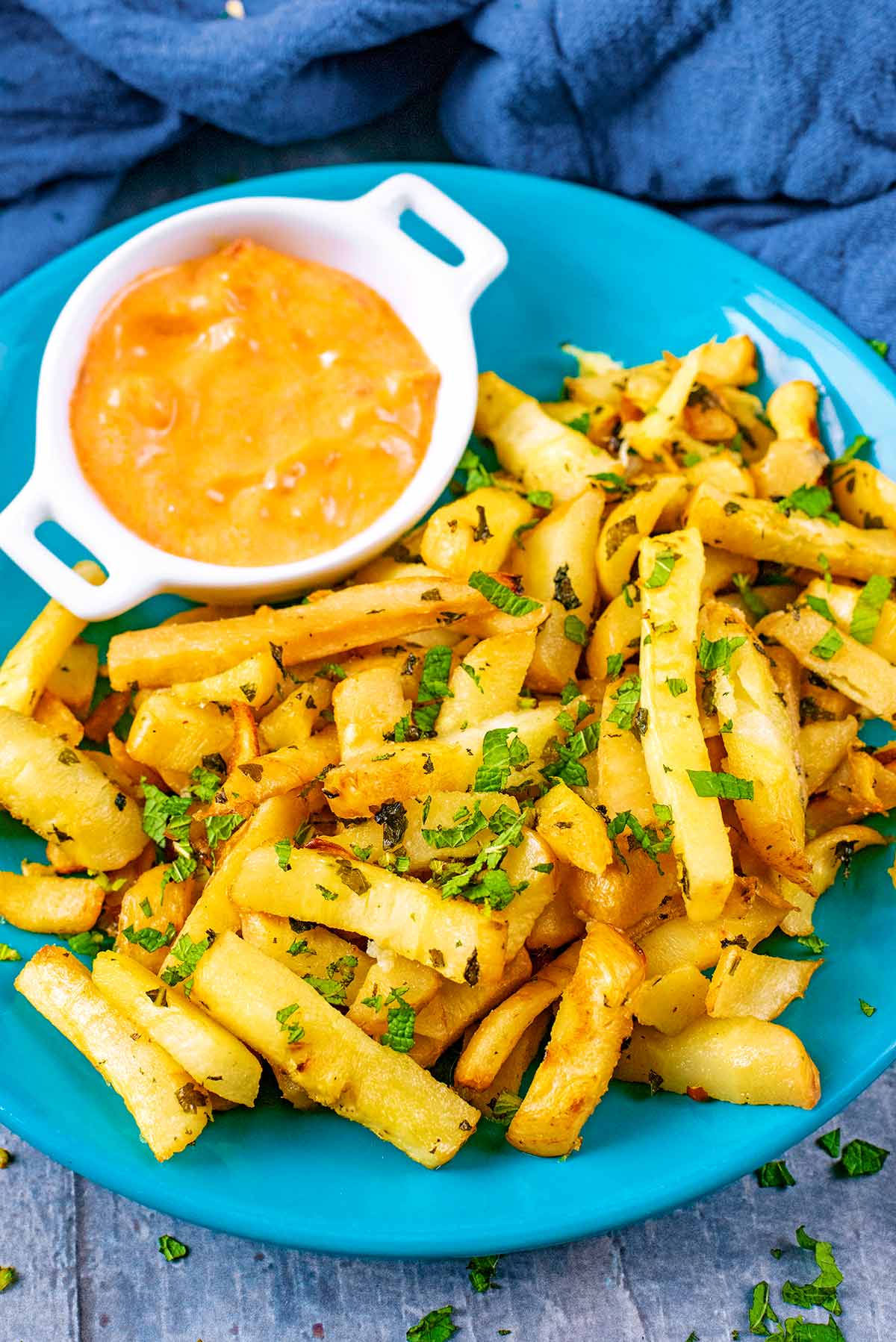 A blue plate with parsnip fries and dipping sauce.
