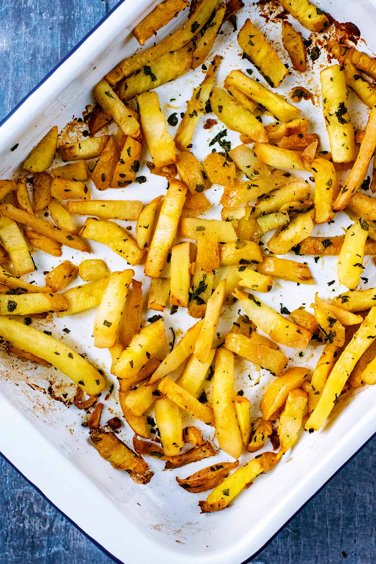 A baking tray containing cooked parsnip fries.