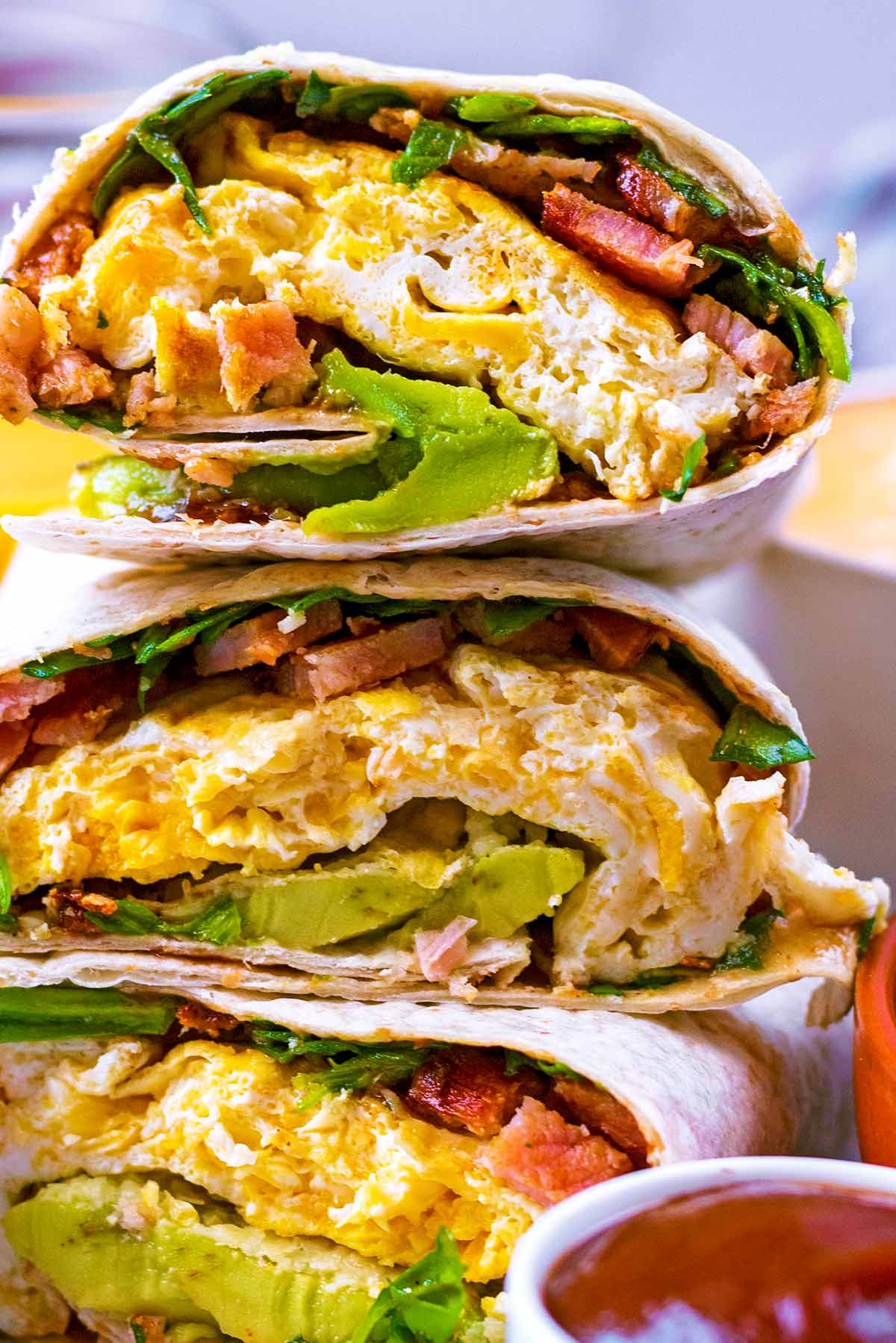 Breakfast wraps showing egg, bacon, avocado and spinach.