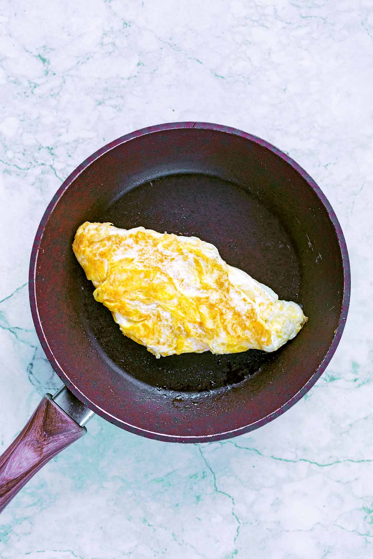 A frying pan with a folded omelette in it