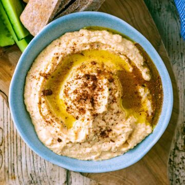 A bowl full of butter bean hummus, toped with oil and spices.