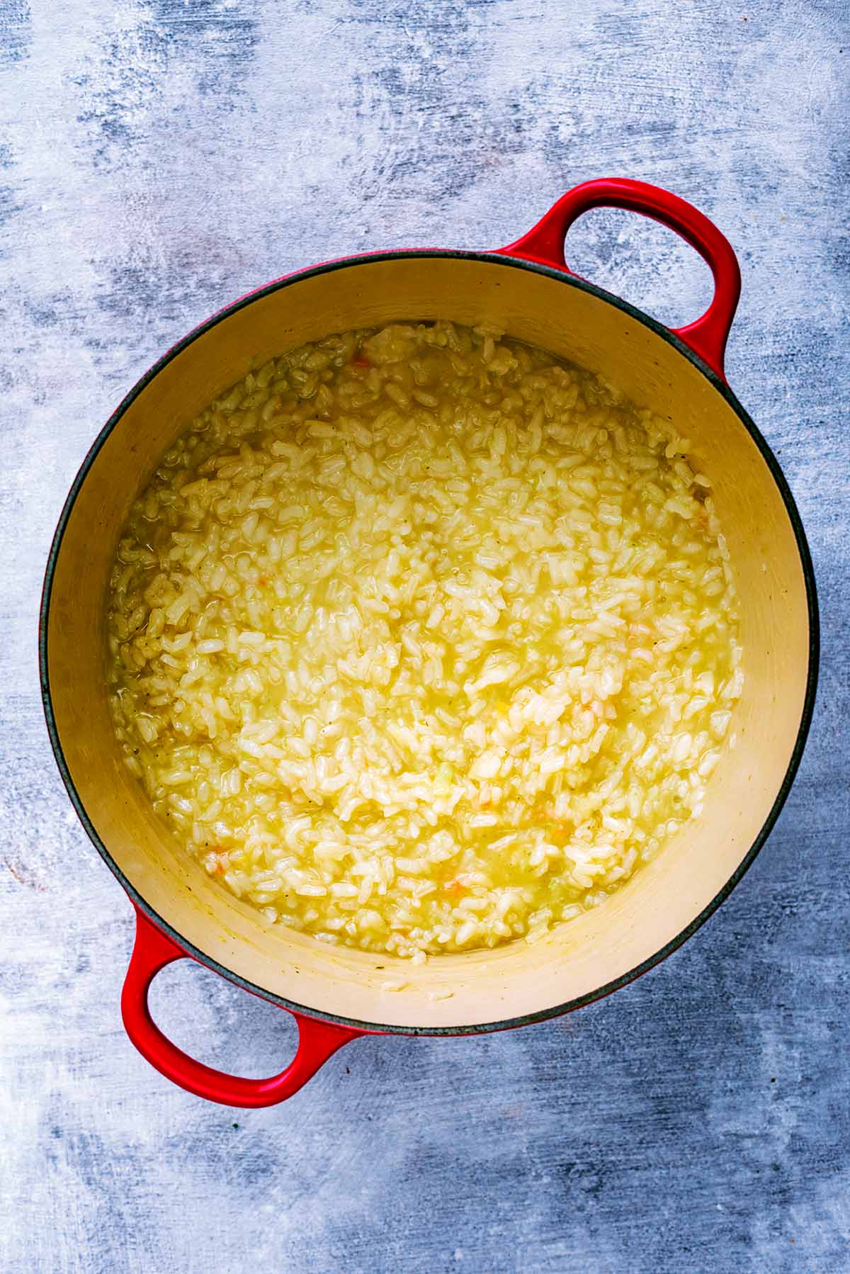 A large red pan containing cooked risotto rice.