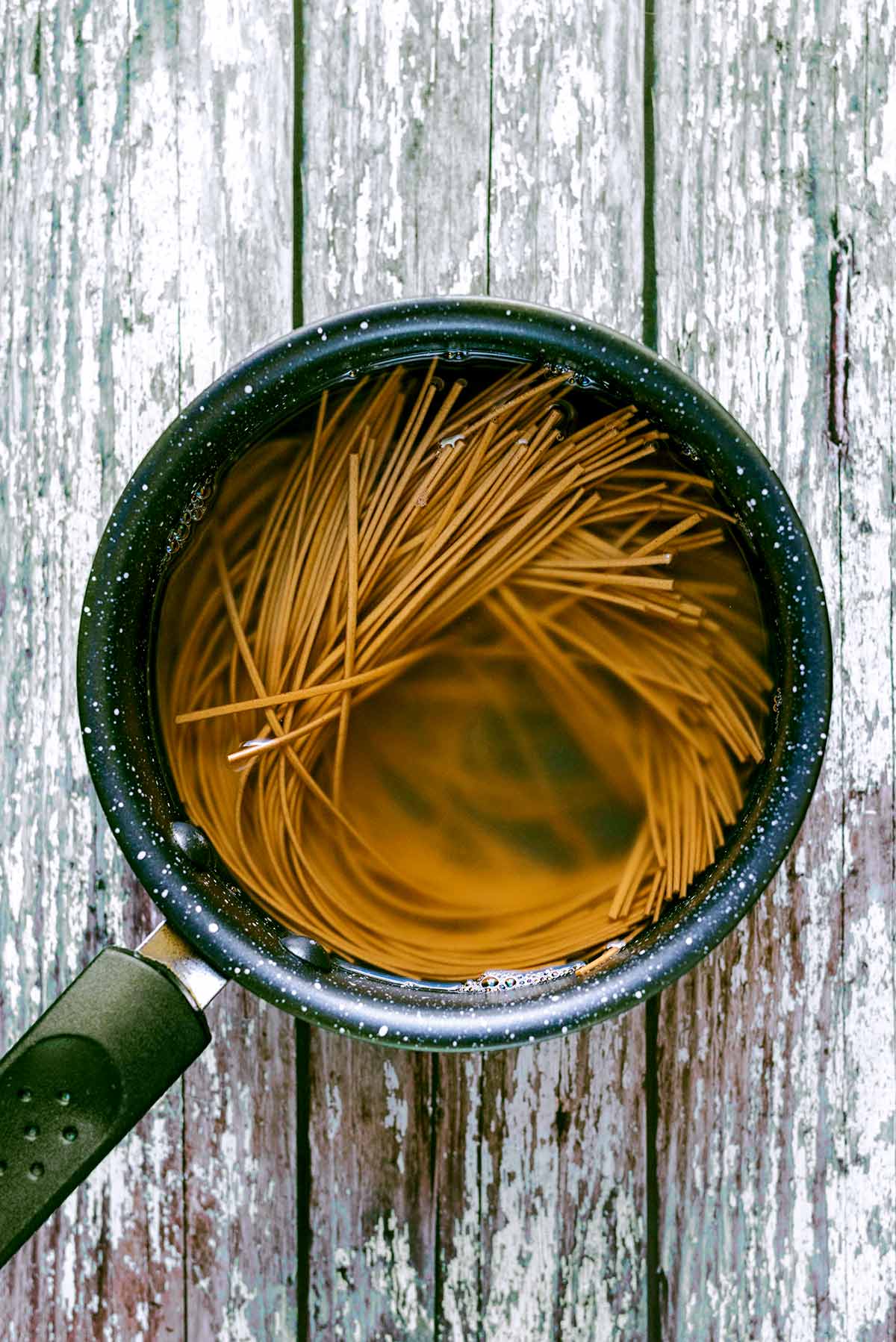 Wholewheat soba noodles cooking in a pan.