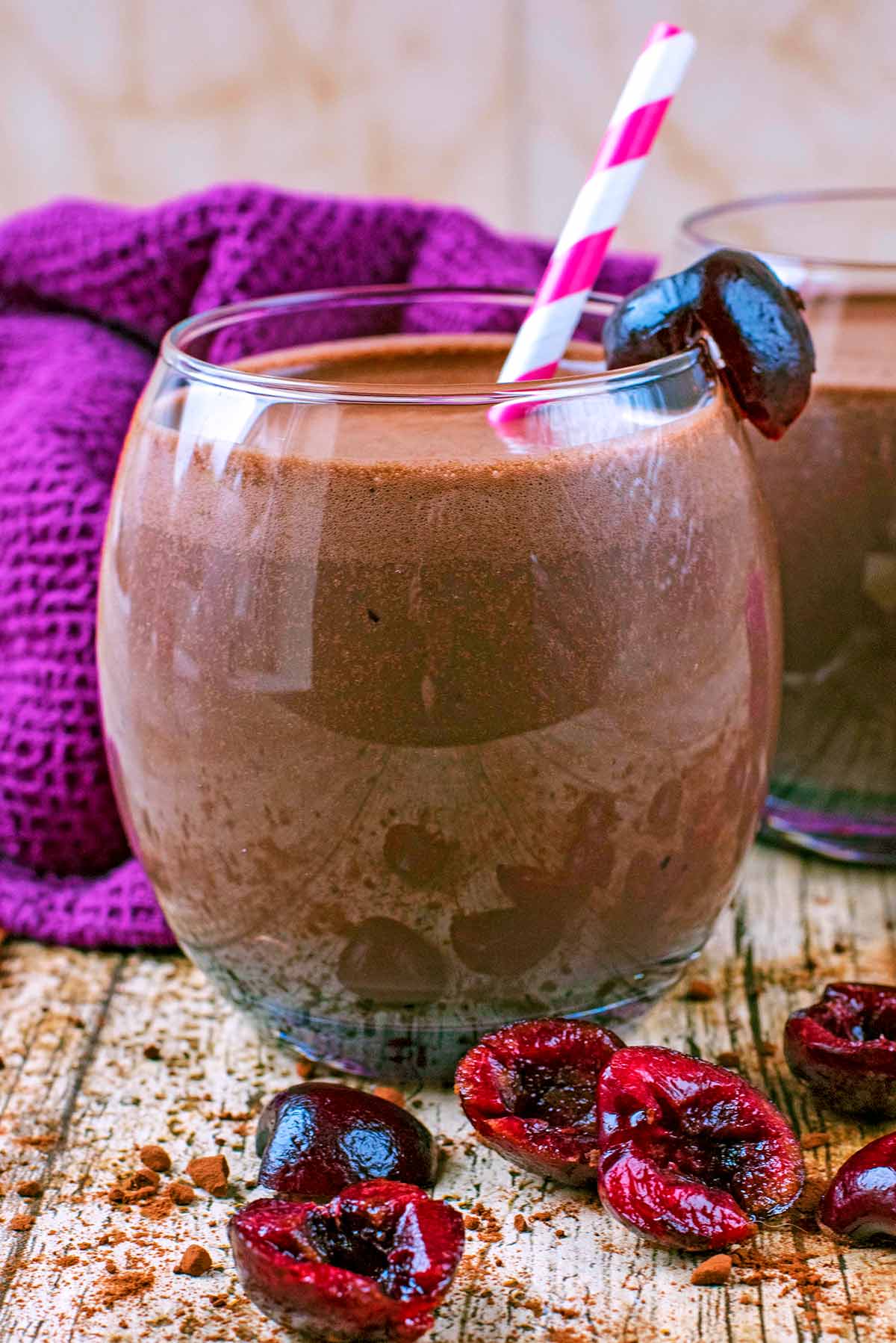 Chocolate Smoothie in a tumbler surrounded by chopped cherries.