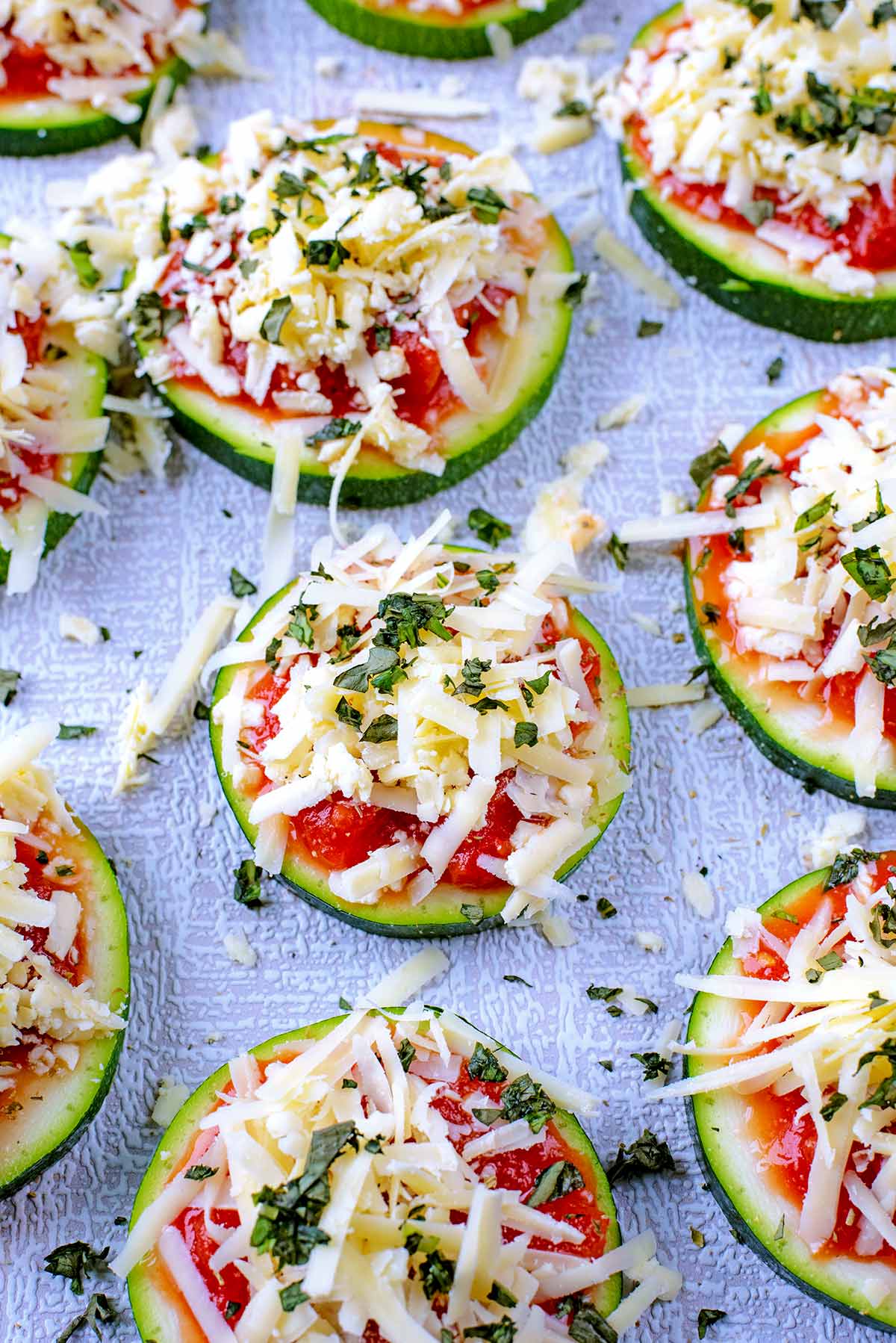 Slices of courgette with tomato and cheese on top.