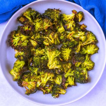 Crispy roasted broccoli on a round plate.