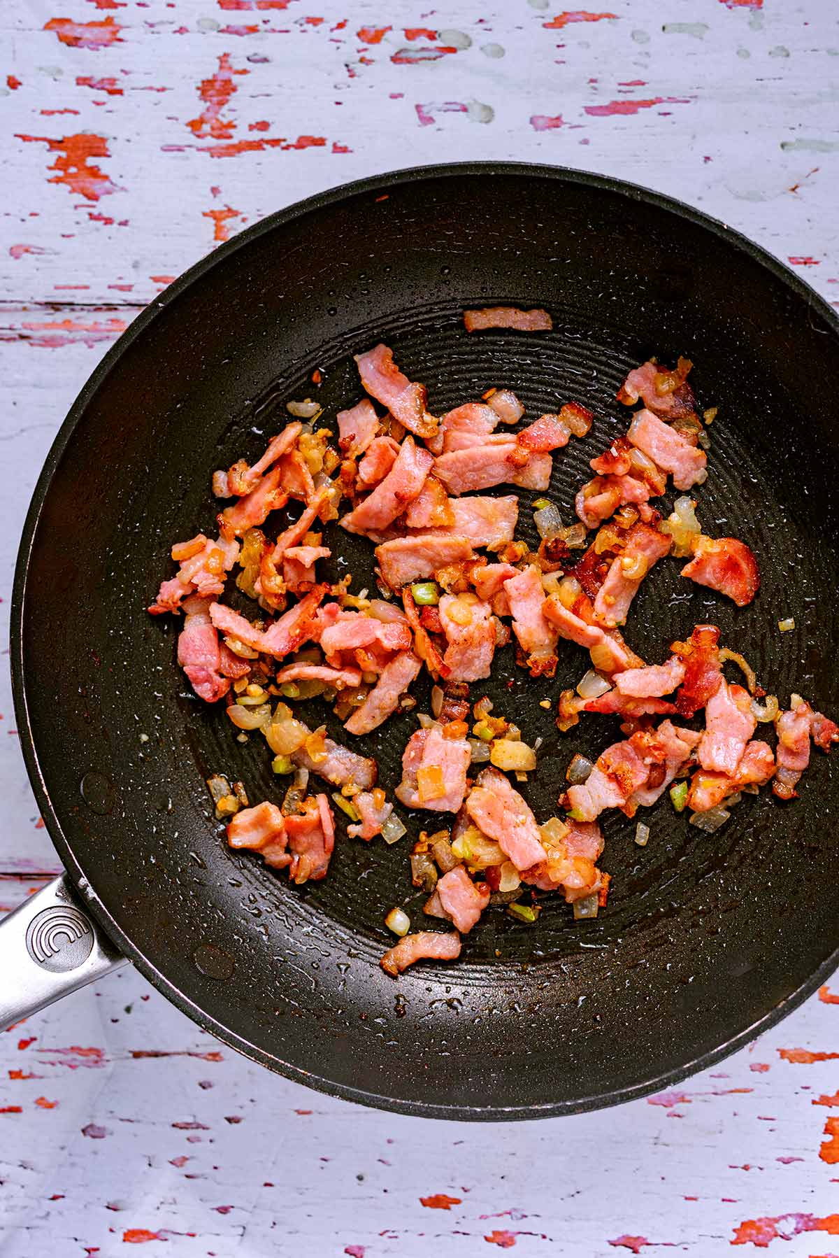 A frying pan with bacon cooking in it.