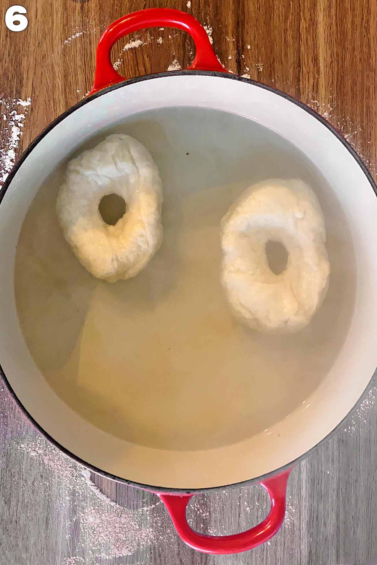 A pan of water with two uncooked bagels floating in it.