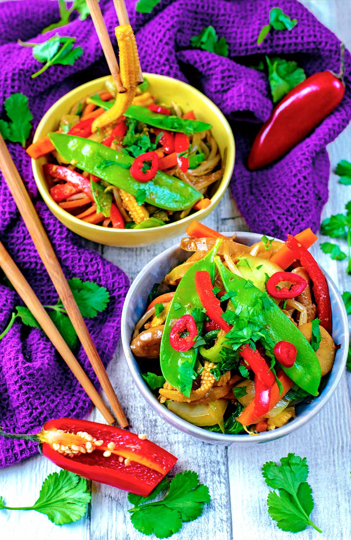 Vegetable stir fry in two bowls next to chopsticks.