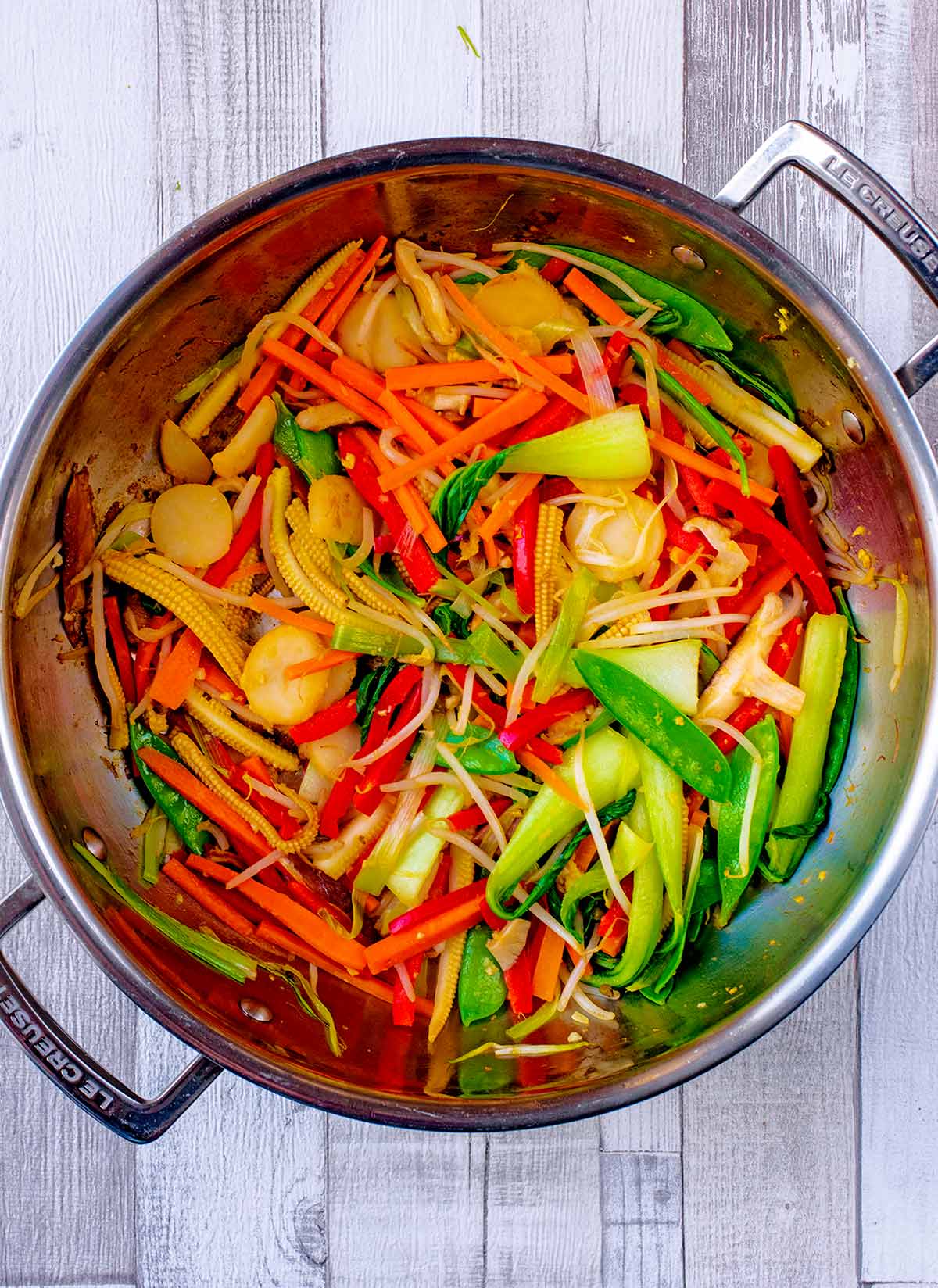 A large silver pan with all the sliced vegetables cooking in it.