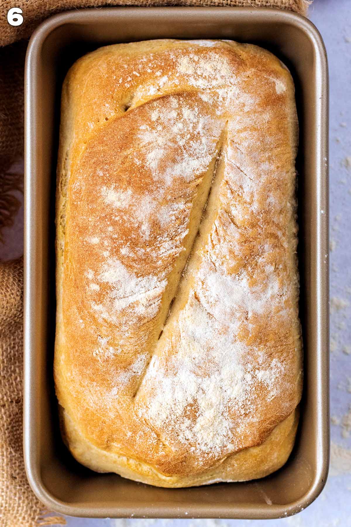 Cooked loaf of bread in a tin.