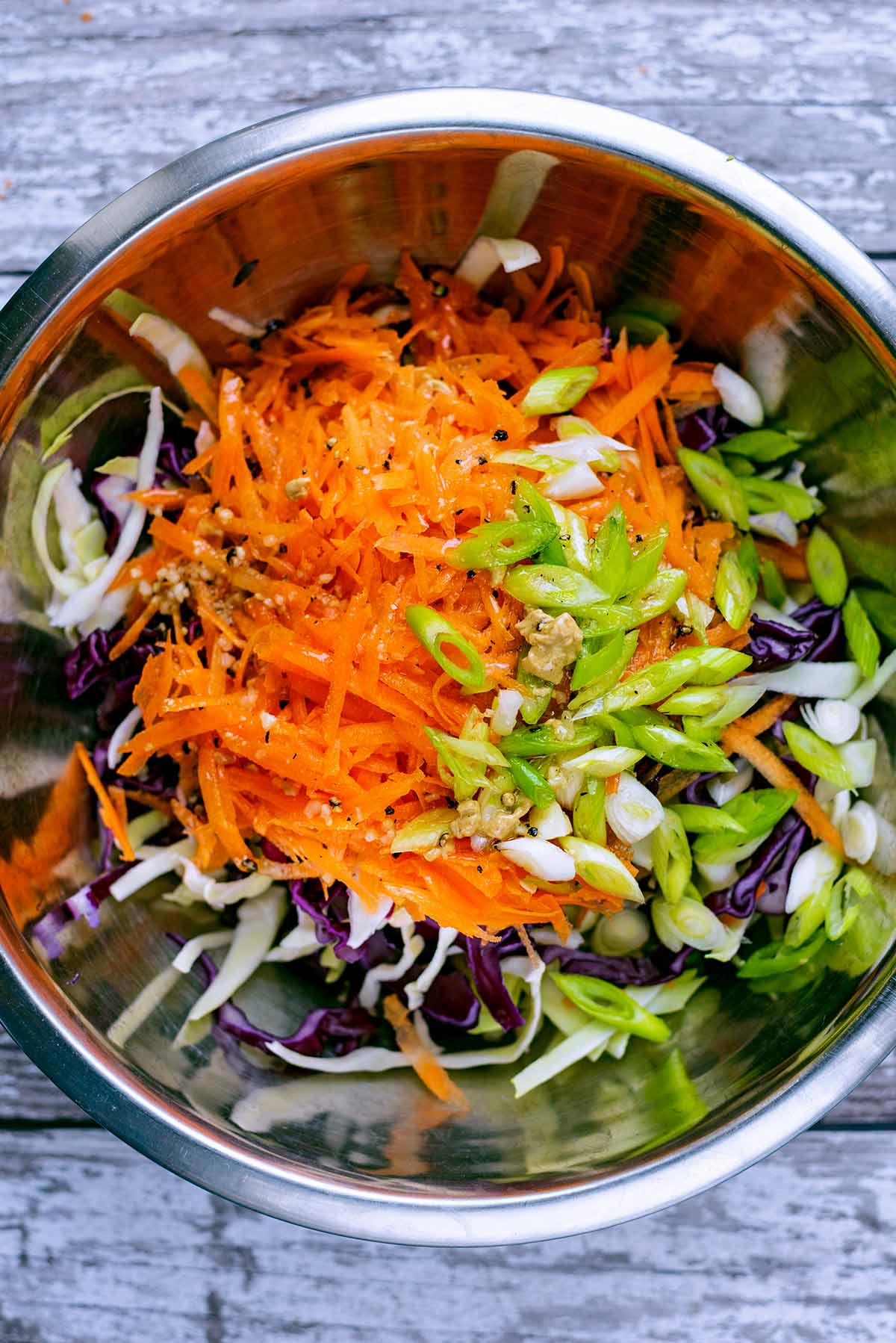 A large mixing bowl containing coleslaw ingredients.