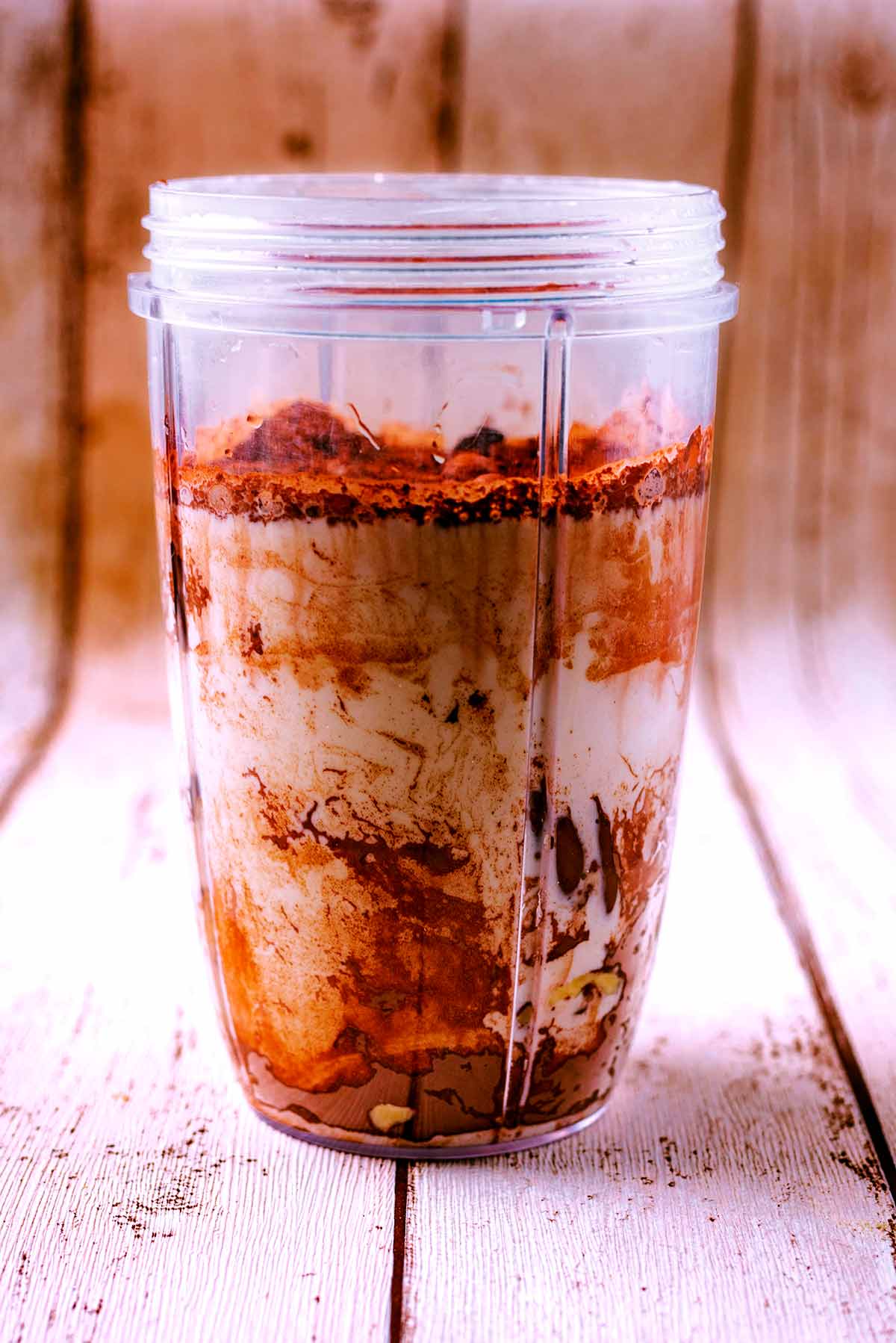 A blender jug with chocolate smoothie ingredients in it.