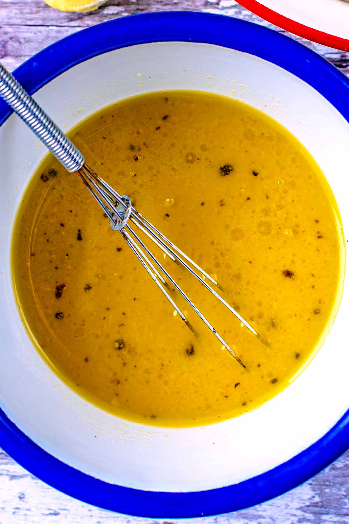 Salad dressing in a bowl with a small whisk.