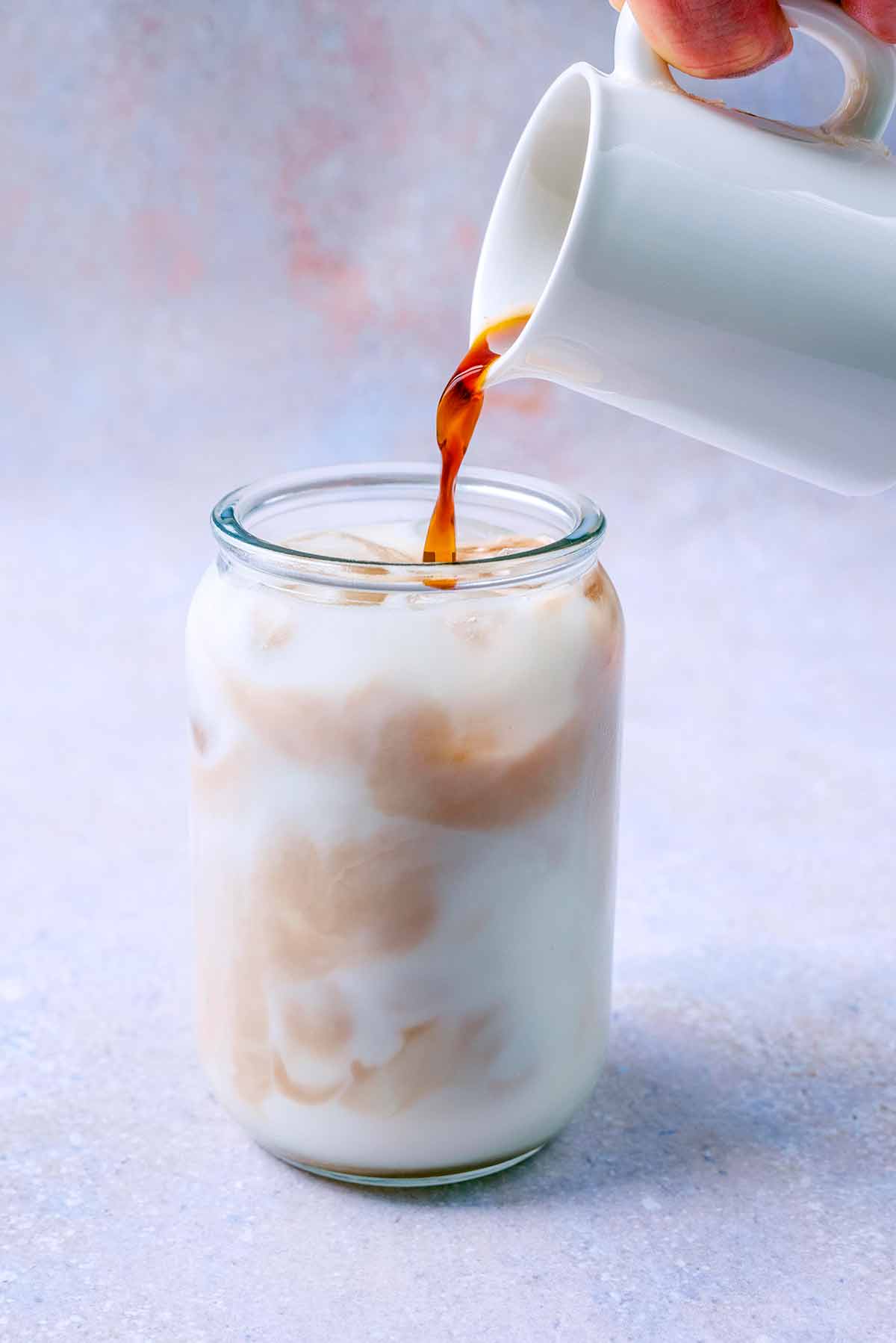 Coffee being poured into iced milk.