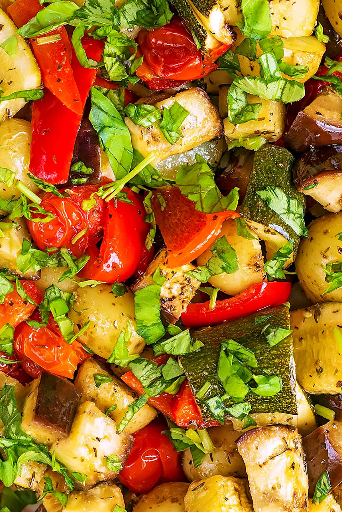 Chunks of potatoes, bell pepper, courgette and aubergine covered in chopped herbs.
