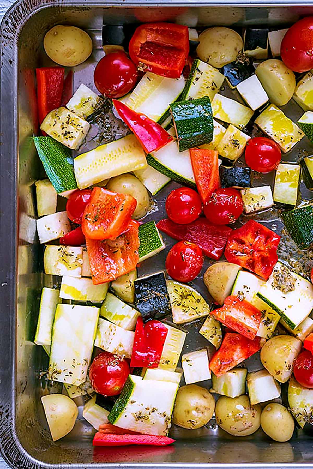 Chopped vegetables in a roasting tin covered in a seasoned dressing.