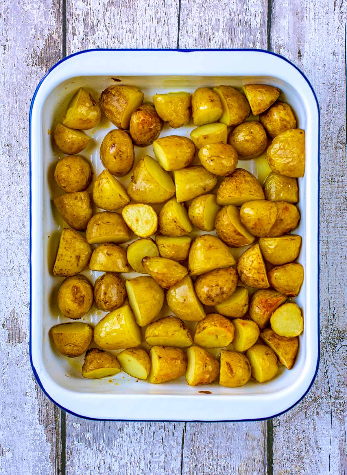 A baking tin containing roasted new potatoes.