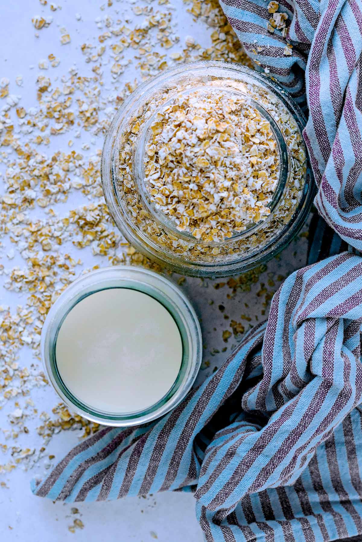A glass of oat milk and a jar full of oats viewed from above.
