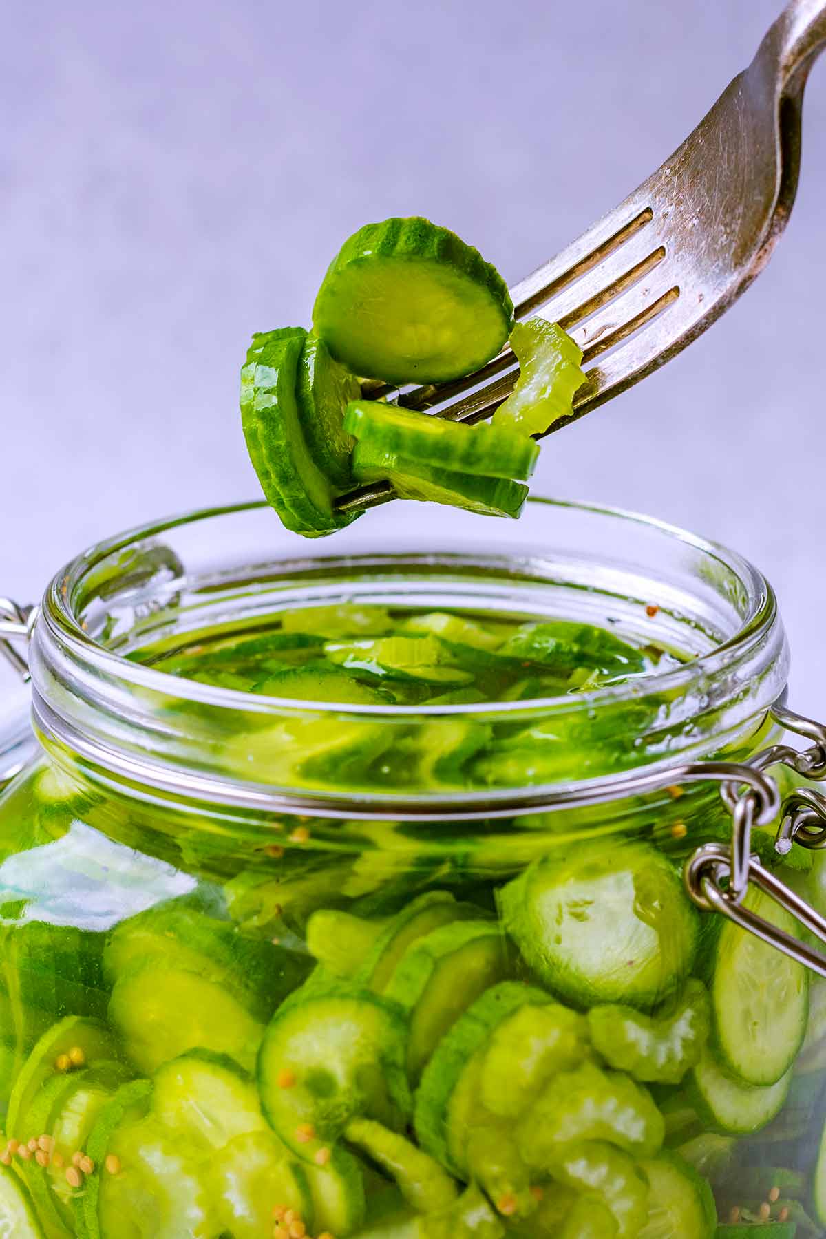 A fork lifting some sliced cucumbers out of a jar.