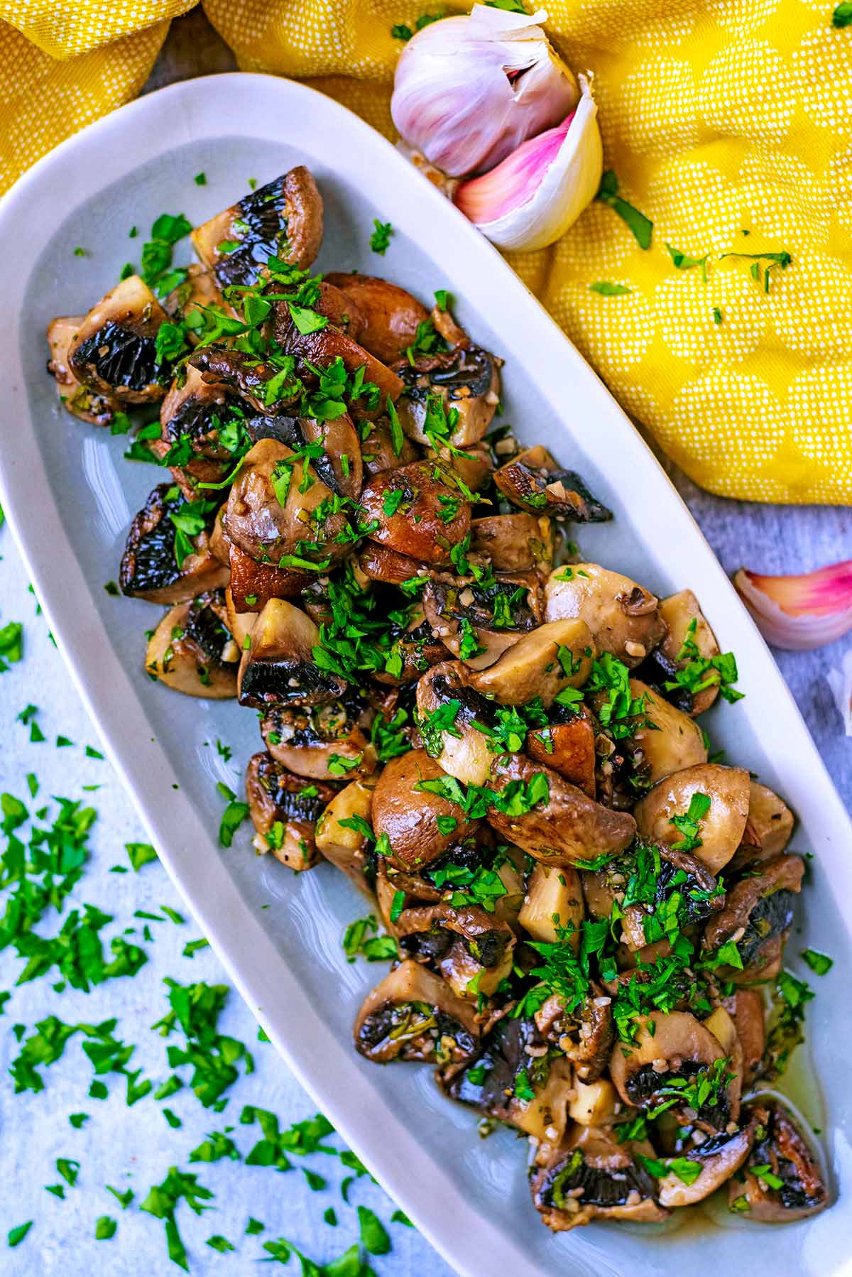 A long serving dish with roasted mushrooms and chopped herbs.