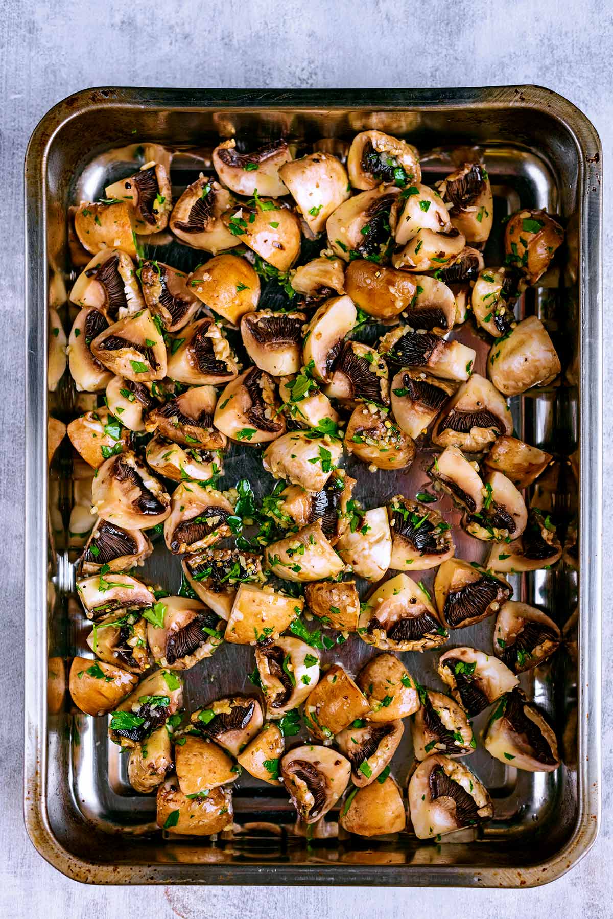 A baking tray covered in chopped mushrooms and herbs.