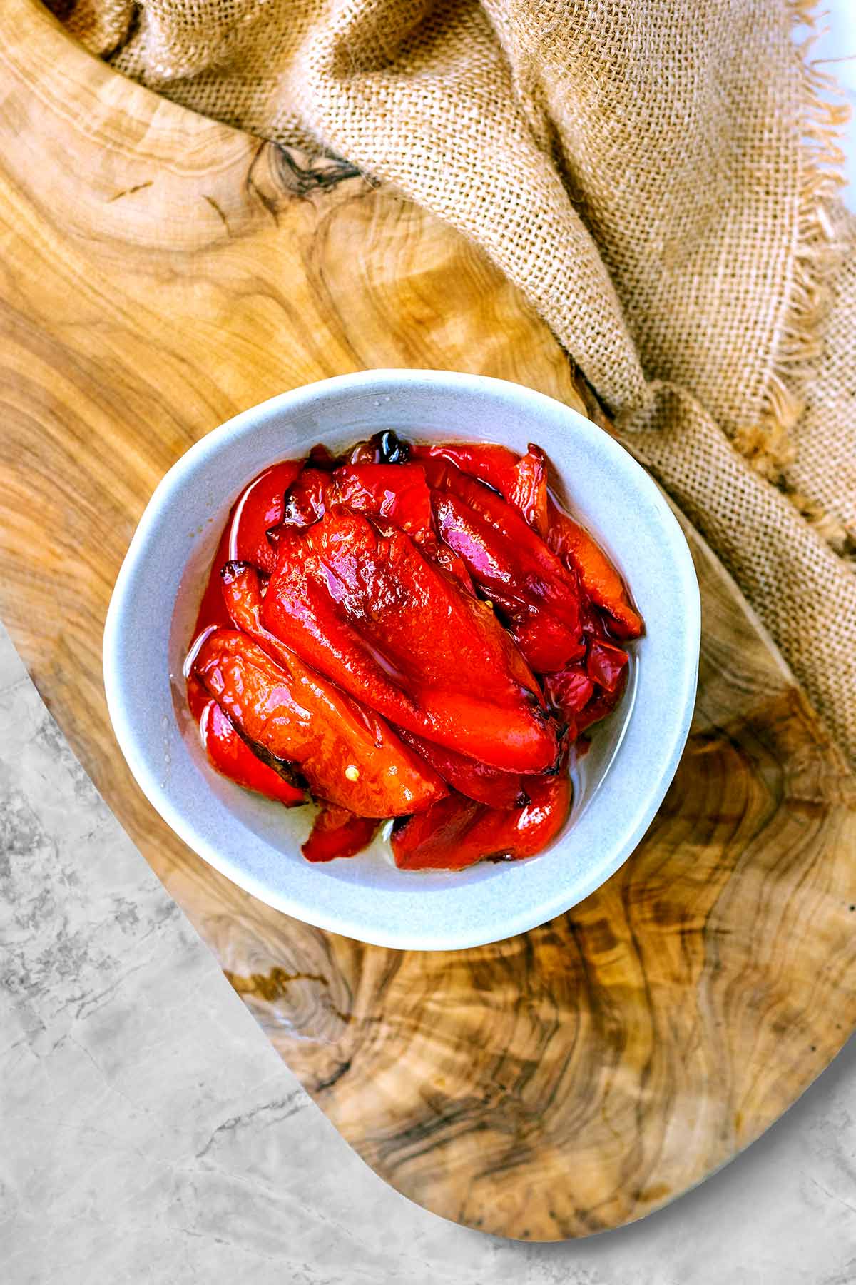 A bowl of roasted red peppers on a wooden serving board.