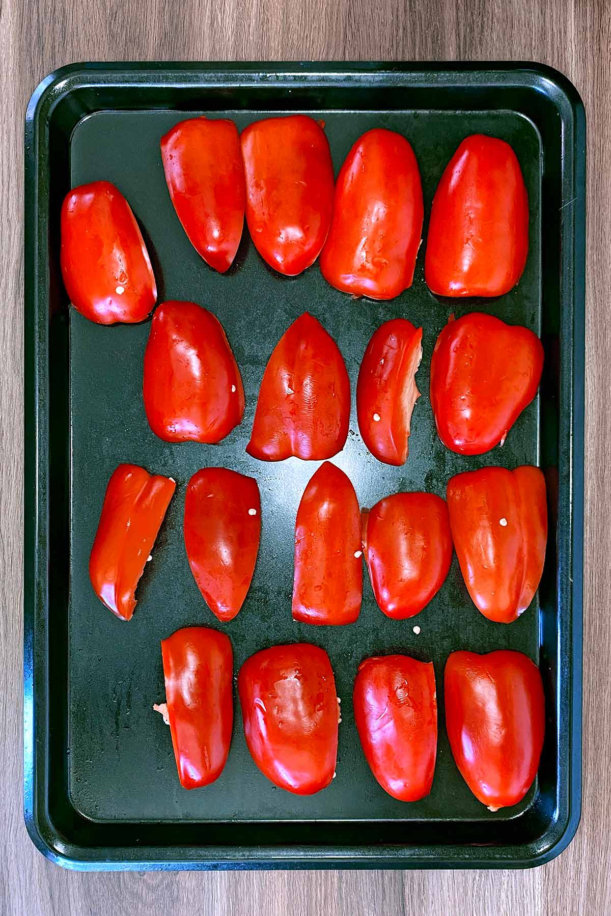 Red pepper quarters on a baking tray.