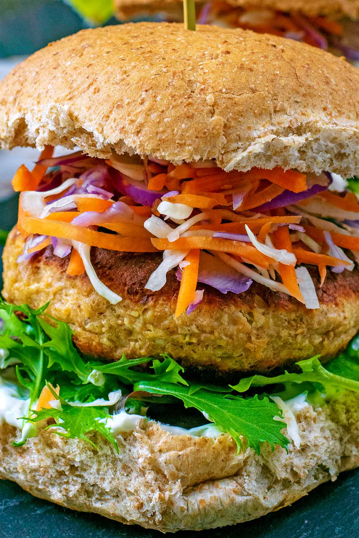 A salmon burger in a bun with lettuce and slaw.