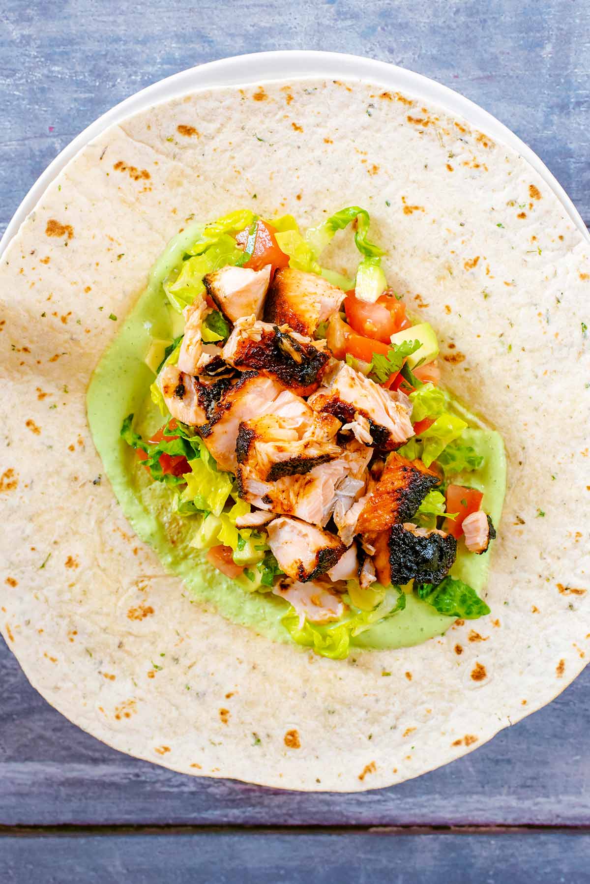 A tortilla wrap with green sauce, chopped salad and flaked salmon fillet.