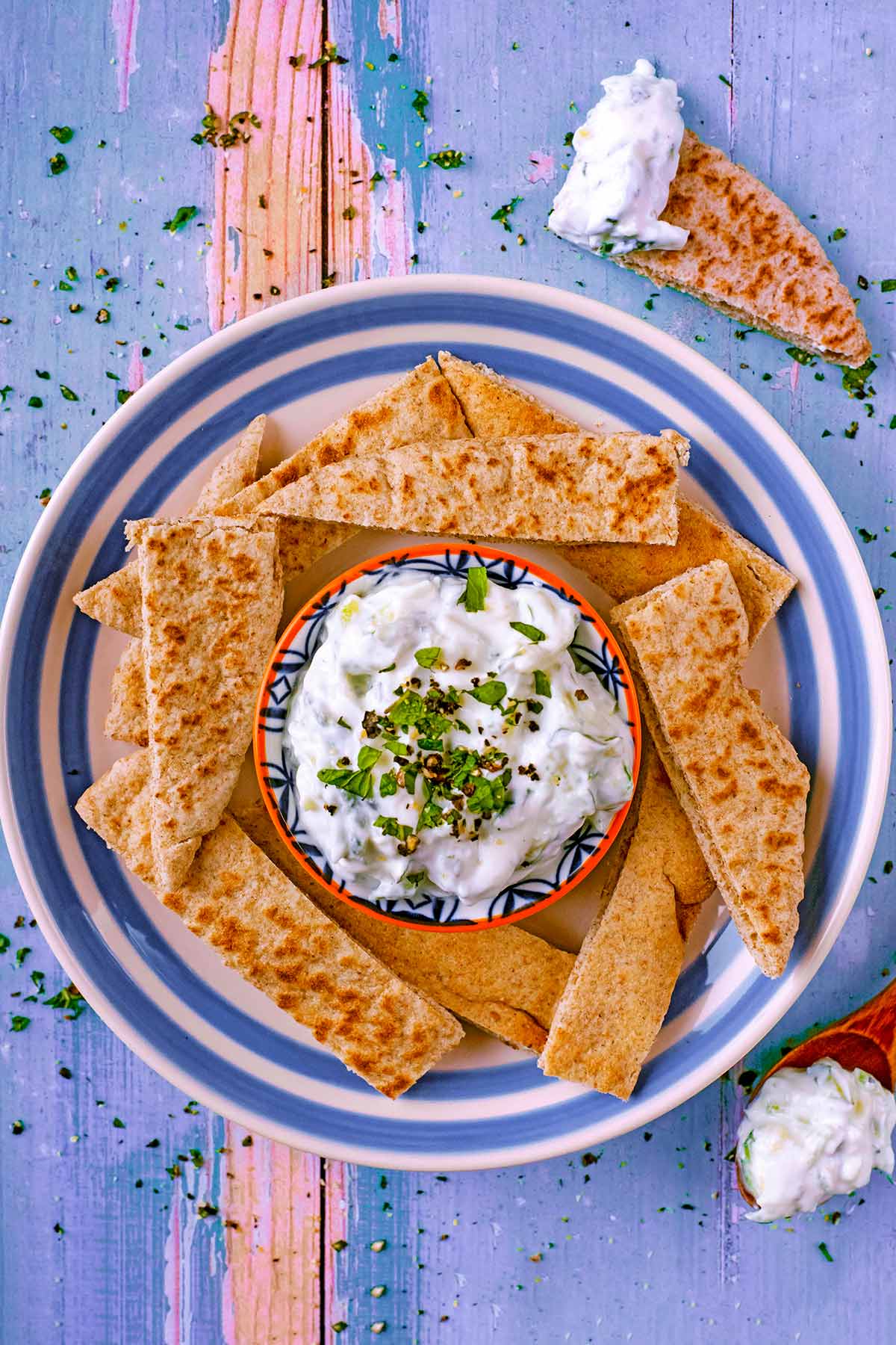 Tzatziki and sliced pita bread on a blue and white plate.