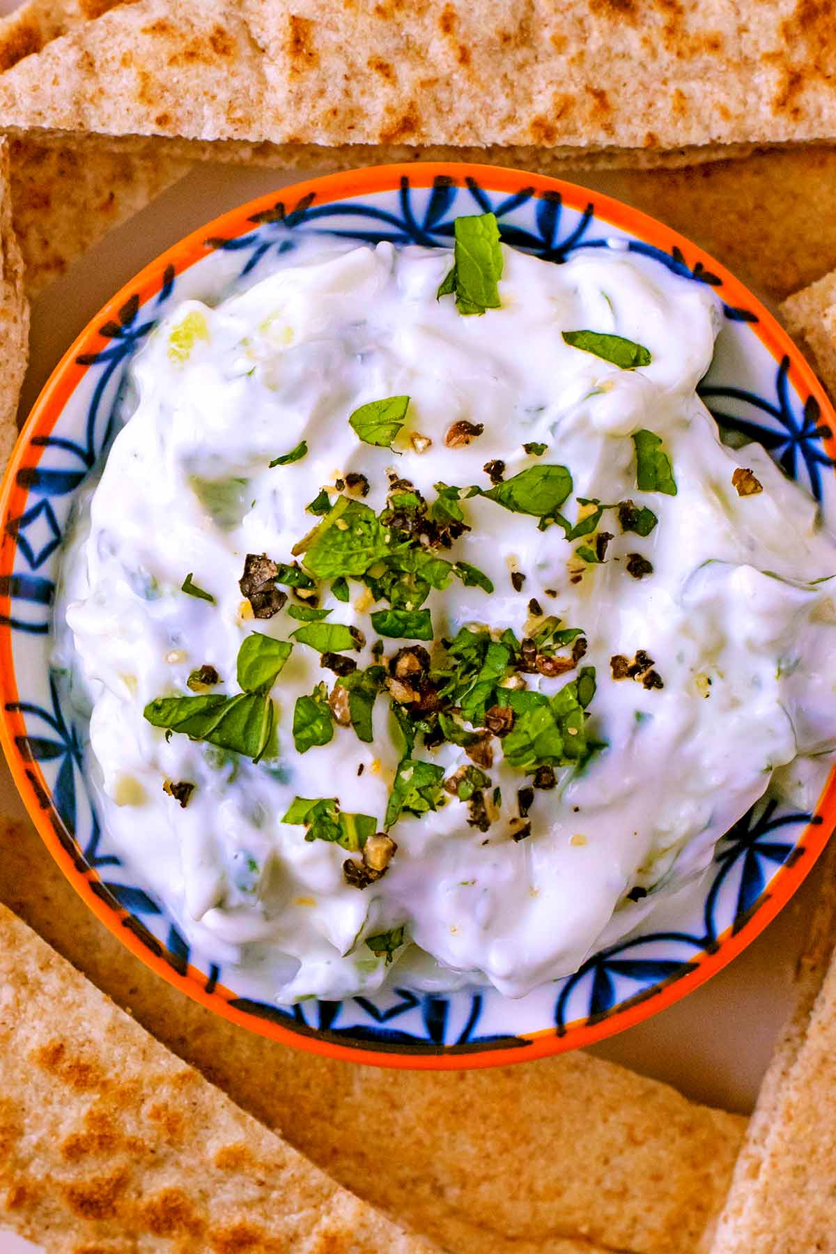 Tzatziki in a small dish topped with chopped mint and ground black pepper.