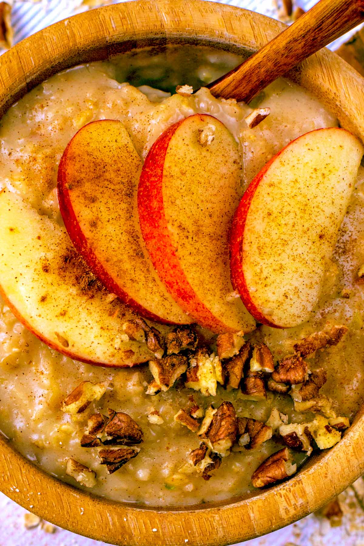 Apple Pie porridge in a brown bowl with apple slices on top.