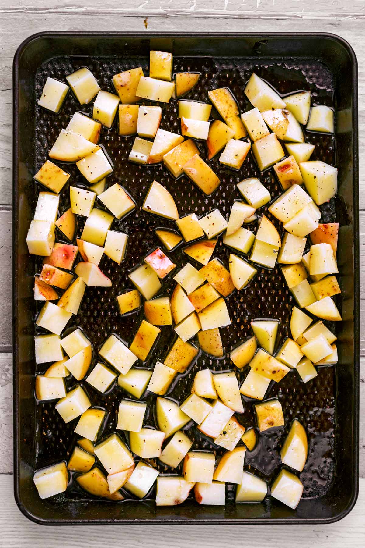A baking tray with cubes of potato on it.