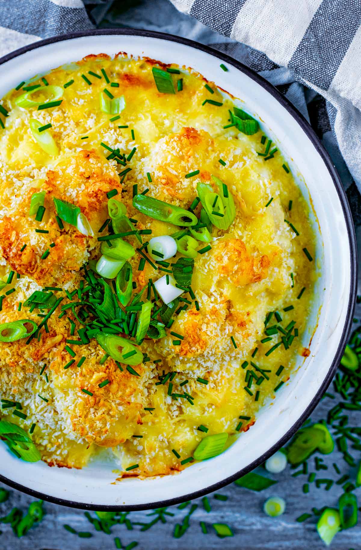 A white bowl full of baked cauliflower cheese.