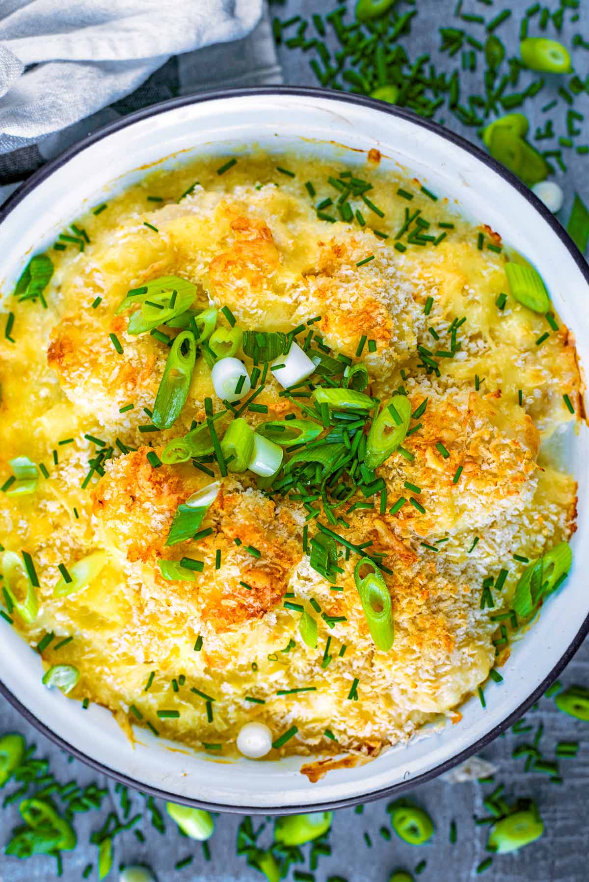Baked cauliflower cheese topped with green onions and herbs.