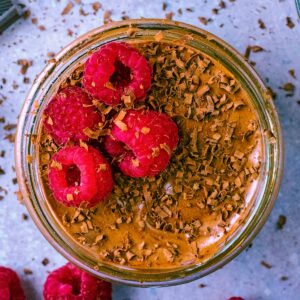Easy Chocolate Mousse in a glass ramekin topped with raspberries.