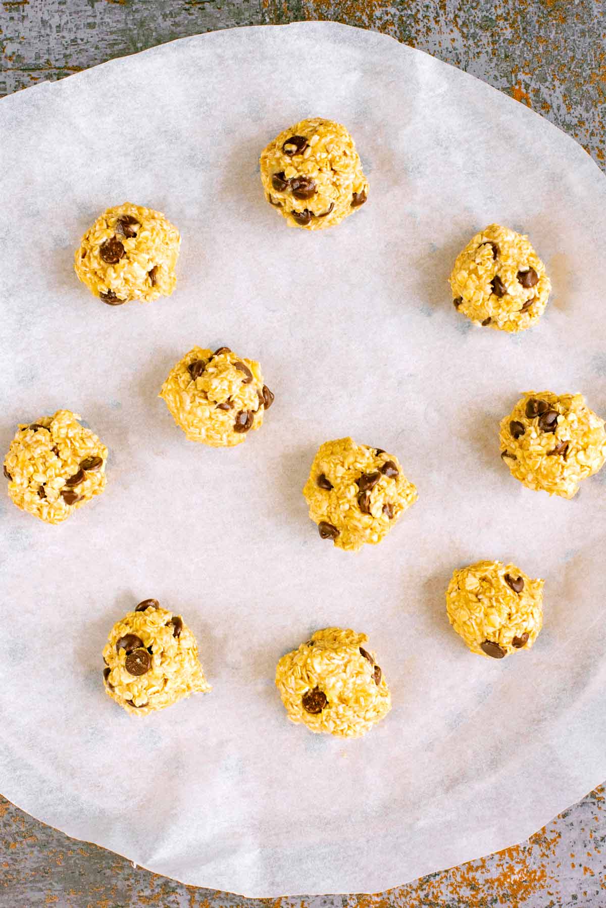 Ten balls of cookie dough on a lined baking tray.