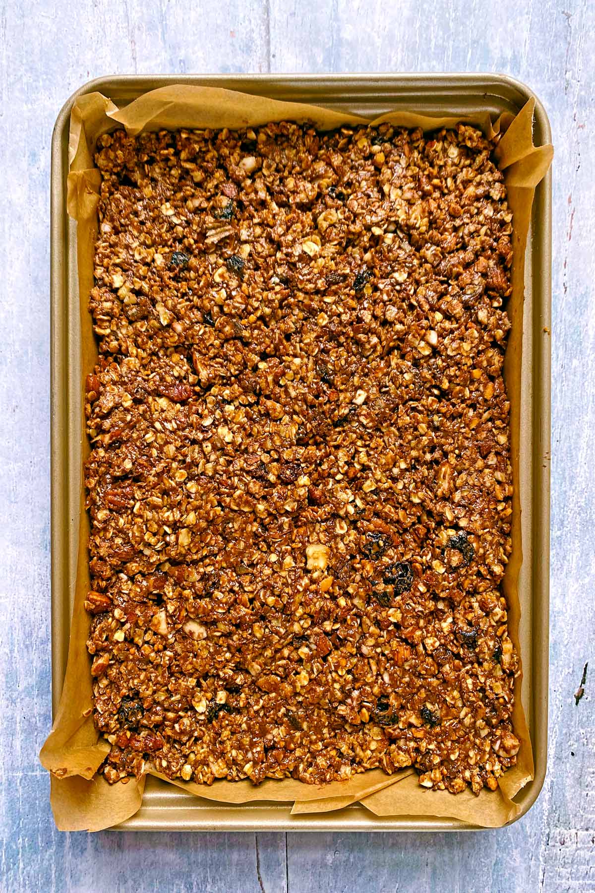 Granola mixture pressed down into a baking tray.