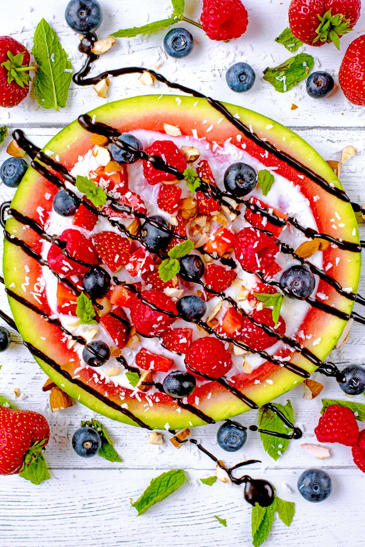 A round slice of watermelon, topped with yogurt and fruit.
