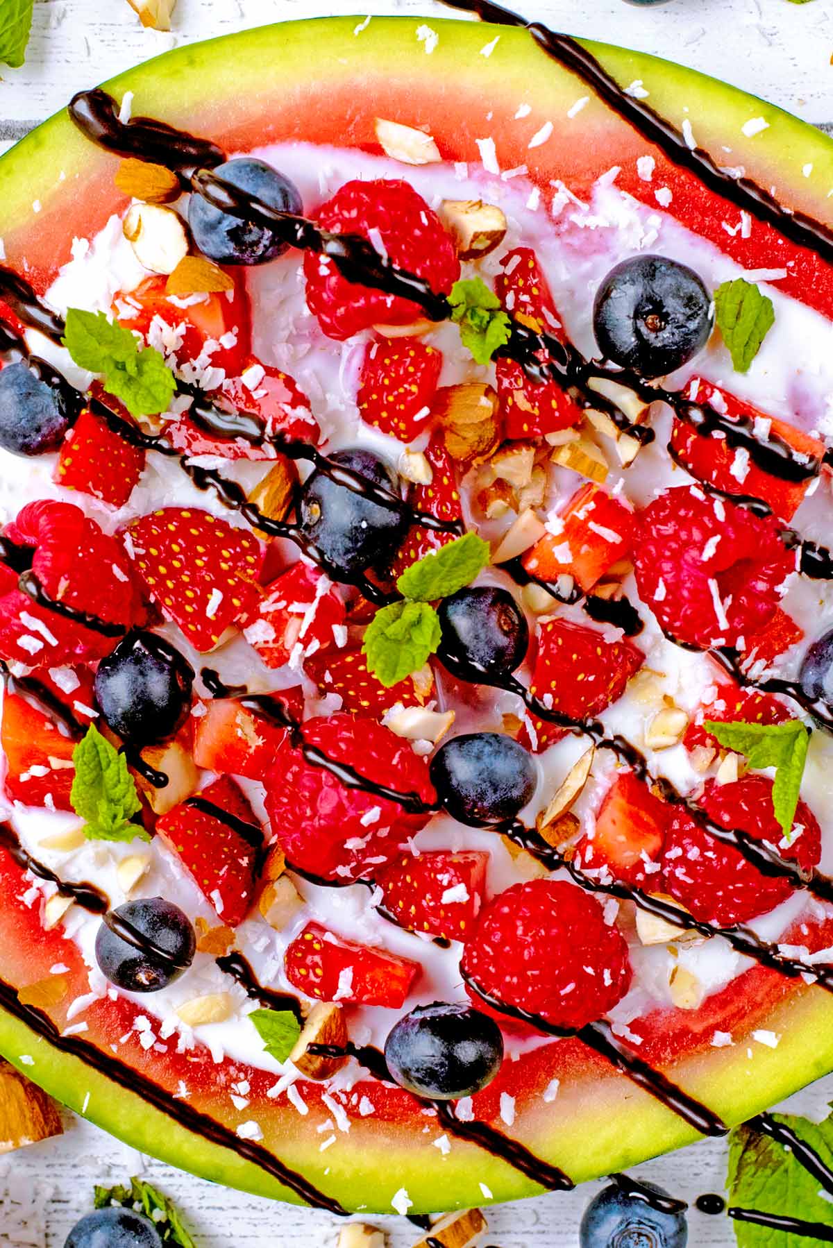 Watermelon fruit pizza drizzled with chocolate sauce.