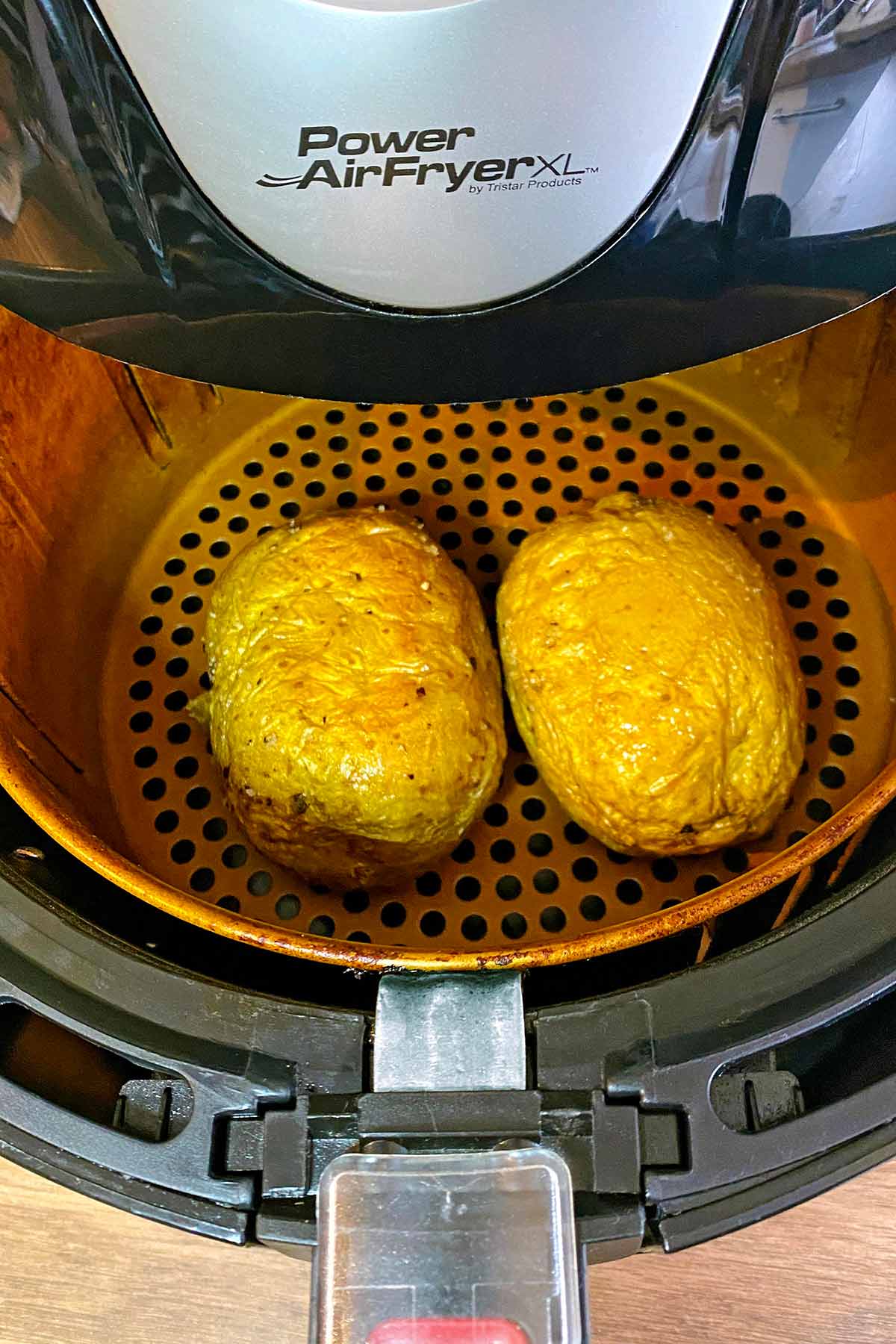 Two cooked potatoes in an air fryer.
