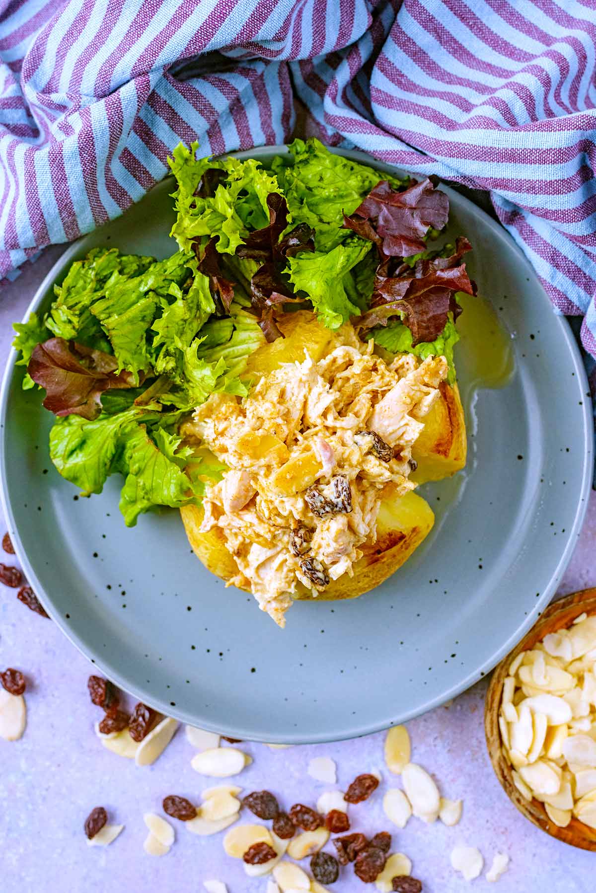 A jacket potato topped with coronation chicken ext to some salad.