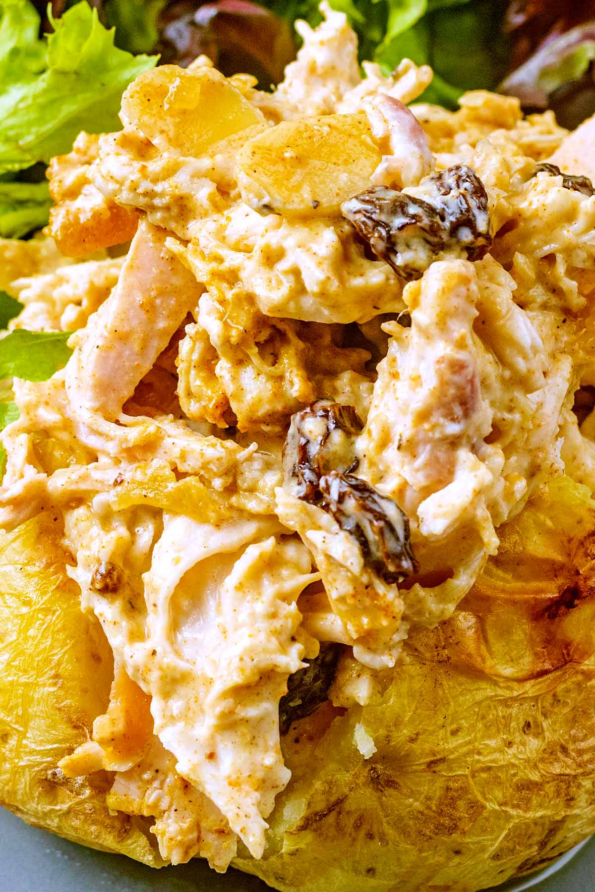 Coronation chicken falling off the side of a baked potato.