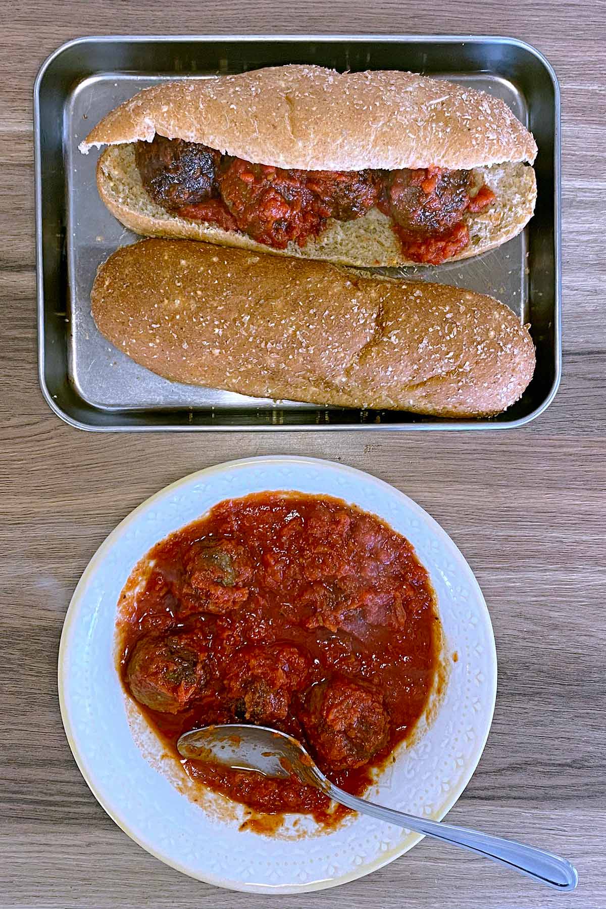 Two sub rolls filled with meatball marinara next to a bowl of more meatballs.